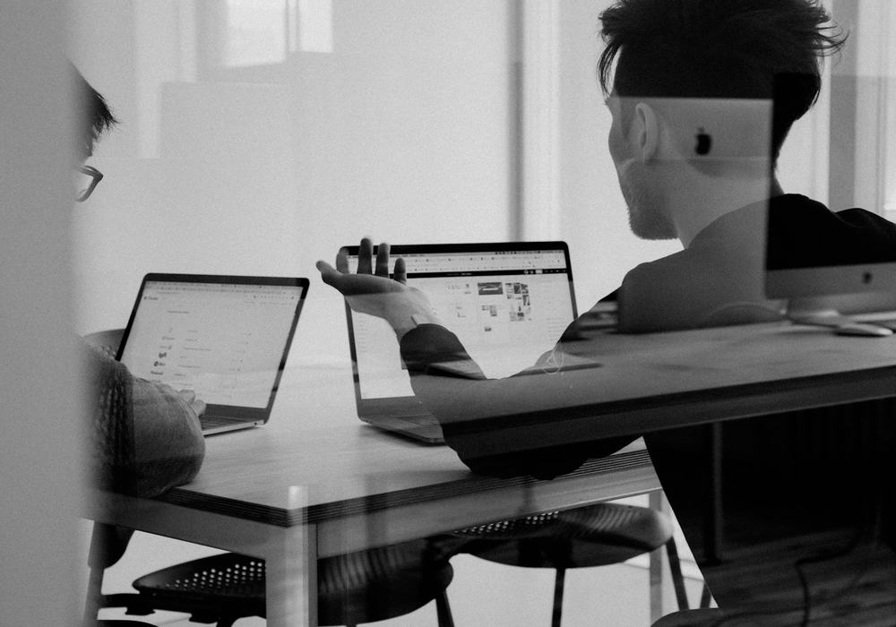 Two people discussing a website on their laptops